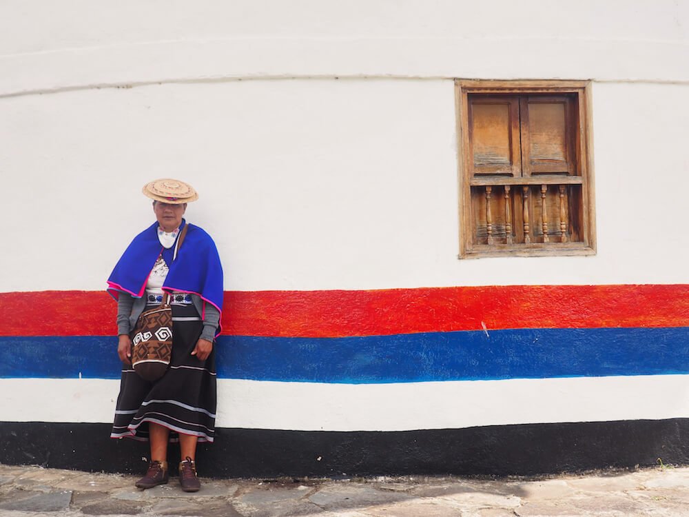 Maria standing in front of a local house
