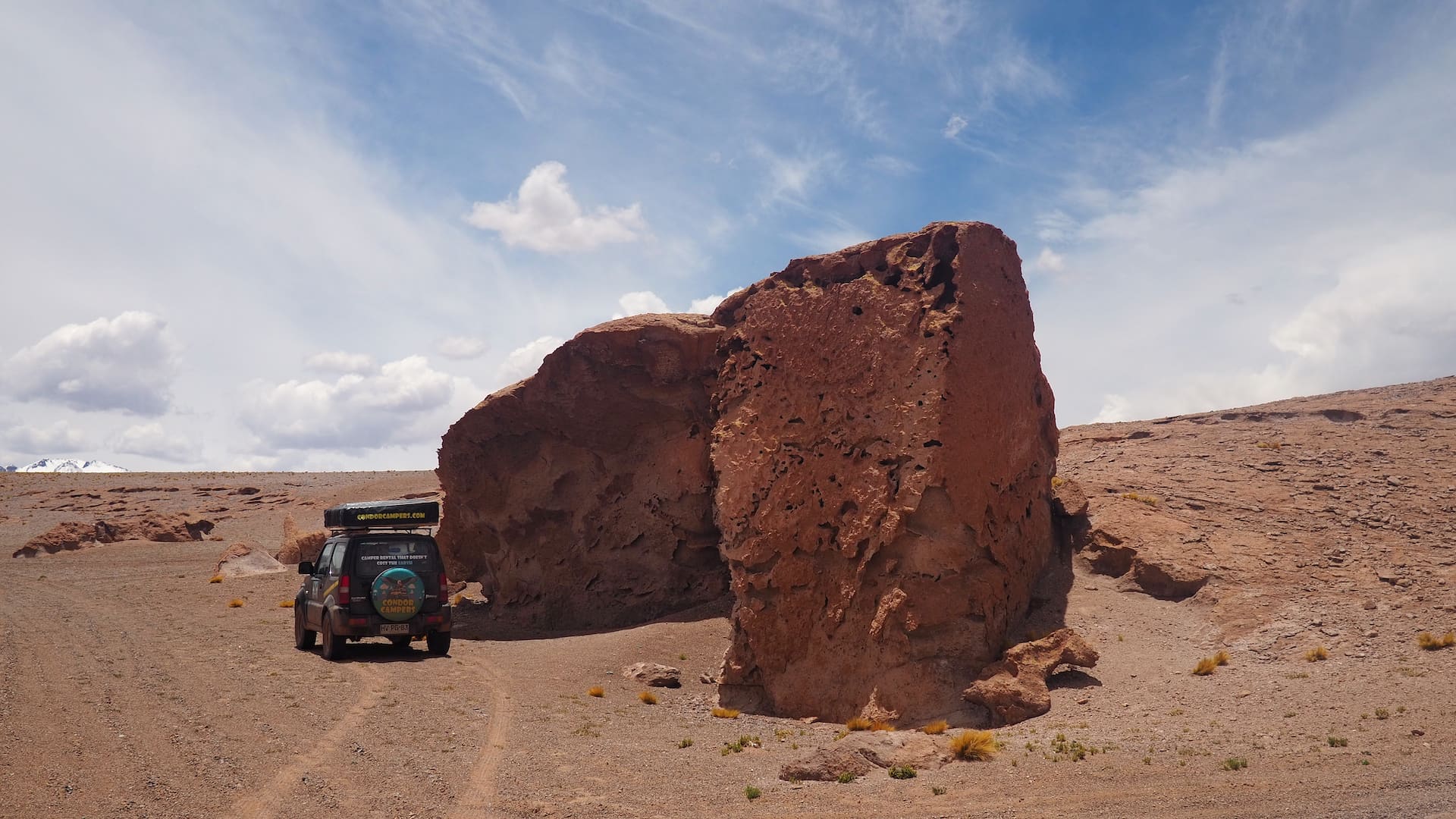 Camper van parked in the shadow of a rock formation