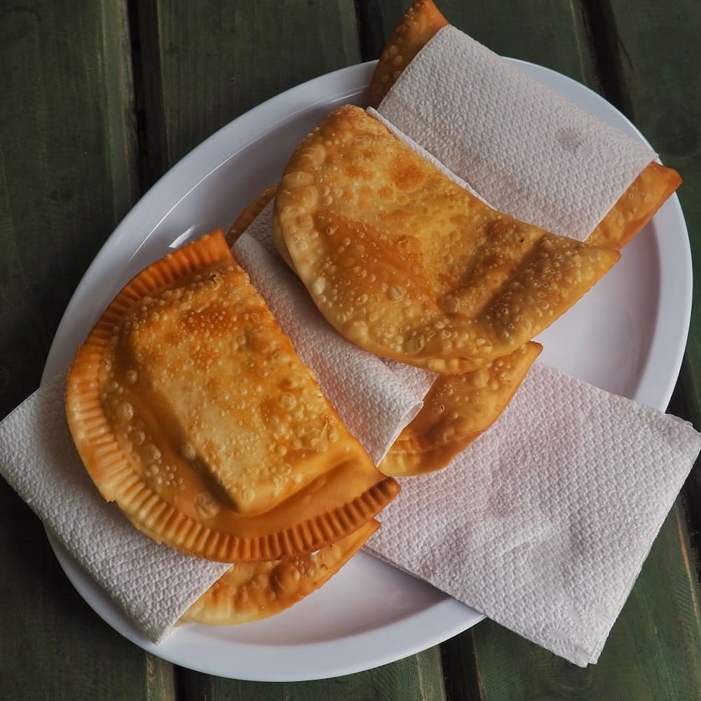 Two cheese empanadas on a paper plate with white napkins