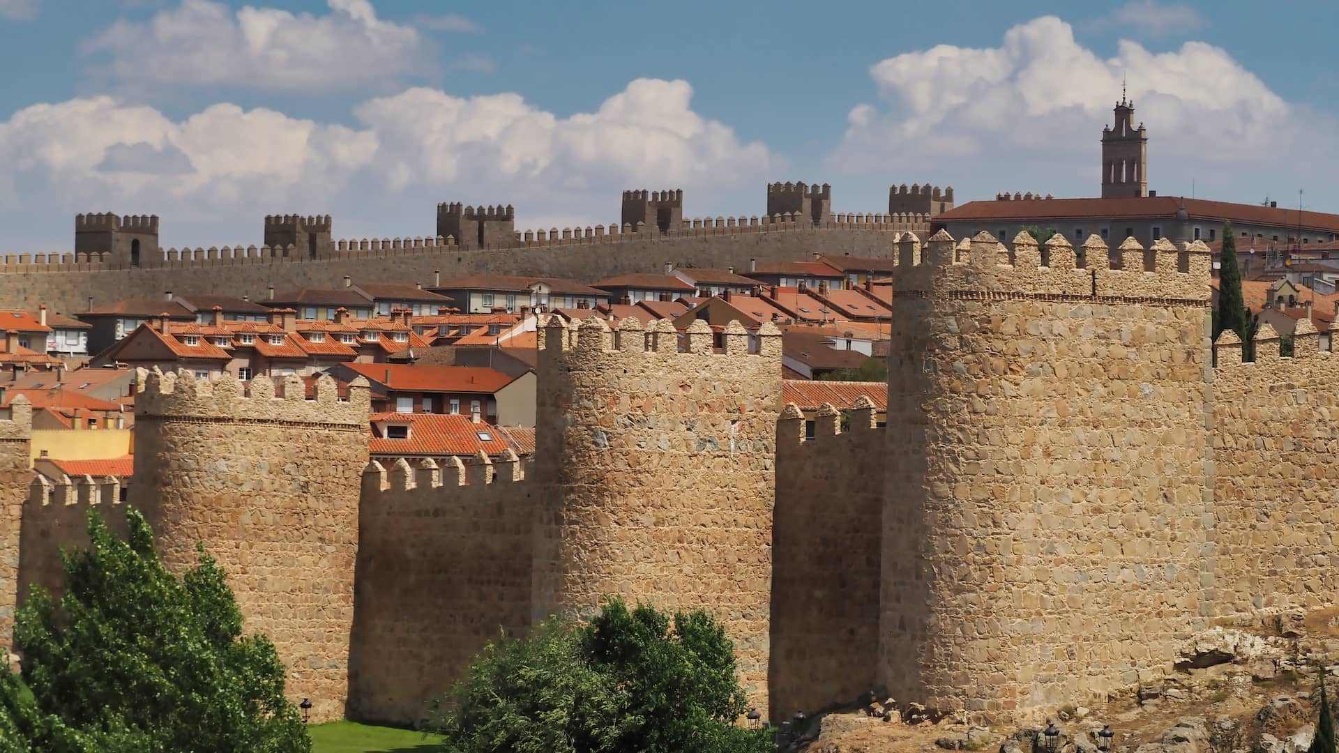 A wall with turrets surrounding red-roofed buildings