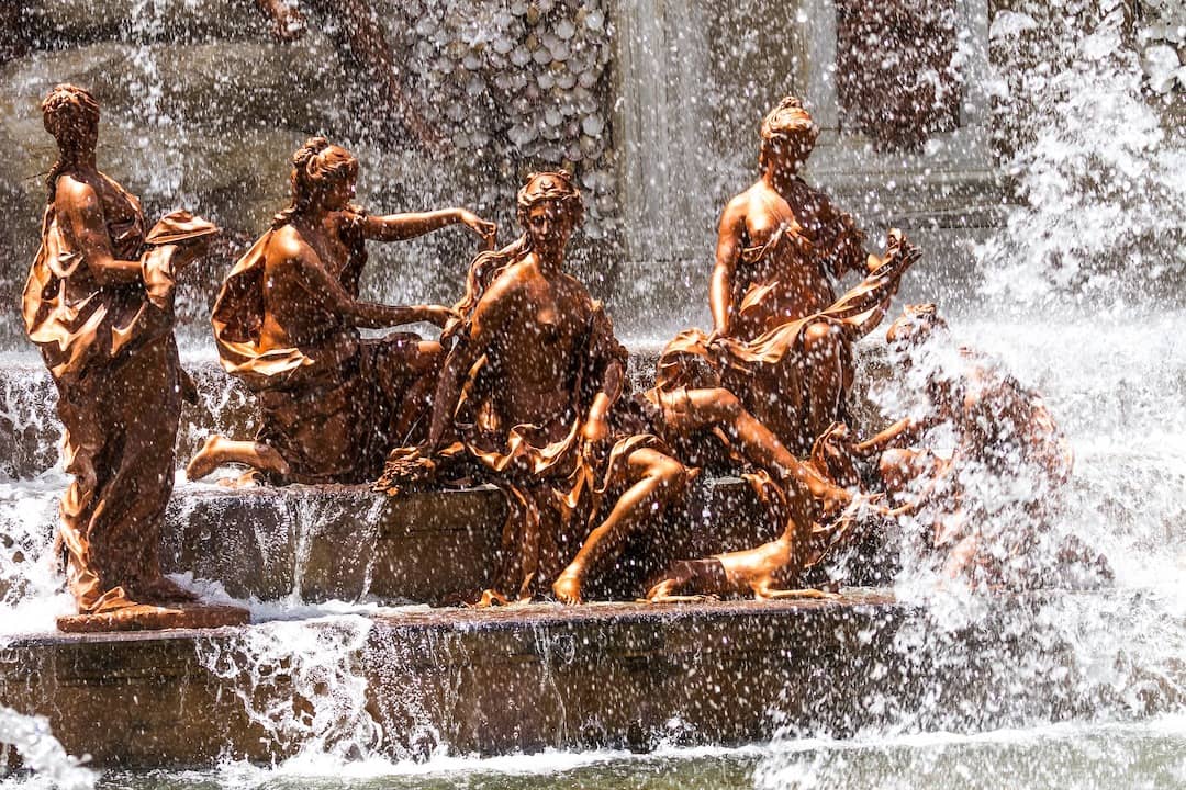 Brass statues engulfed in water from a fountain