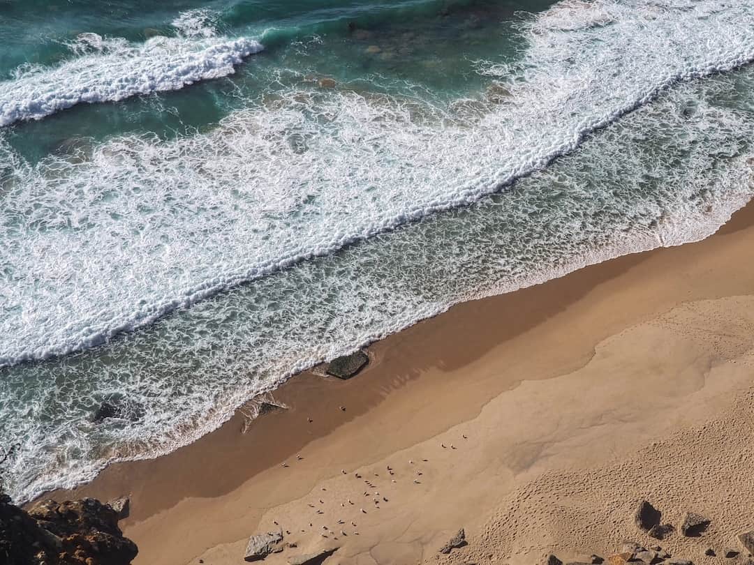 Aerial view of waves crashing on to a golden beach