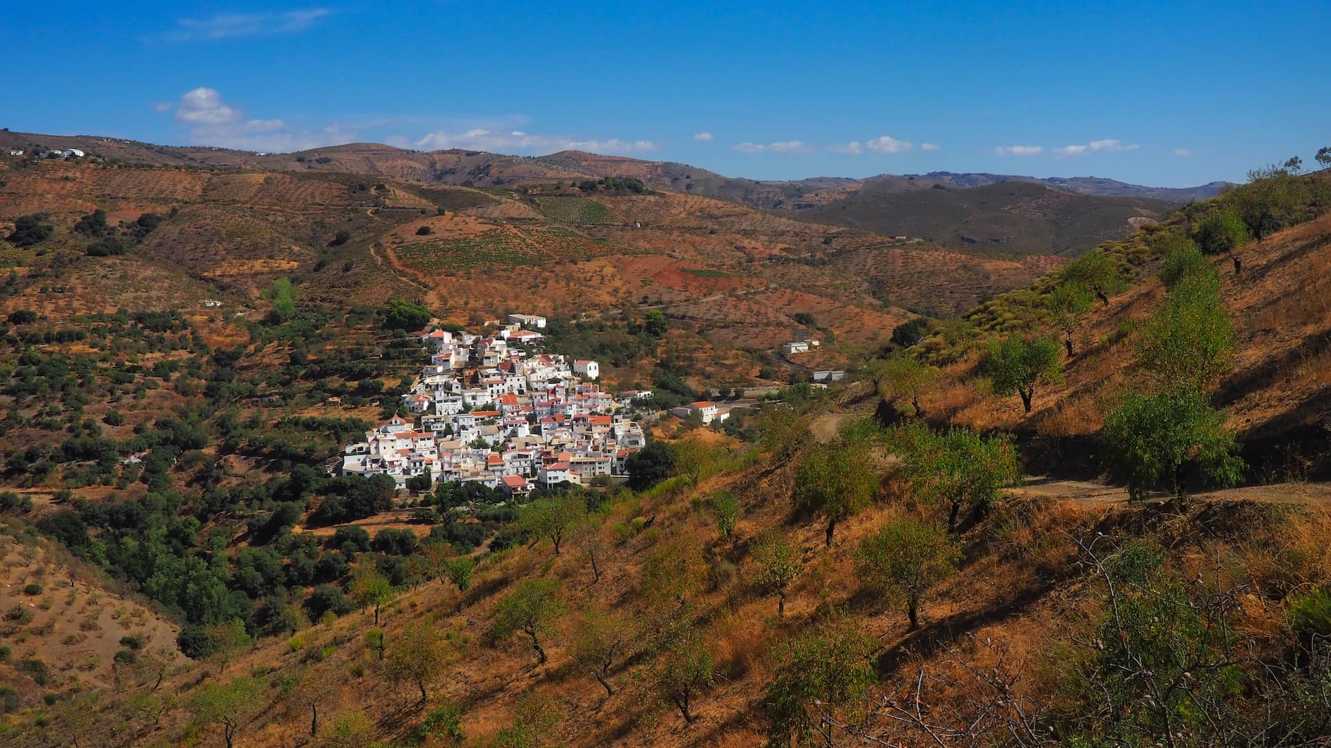 A triangular-shaped village of whitewashed buildings and red roofs clings to a mountainside
