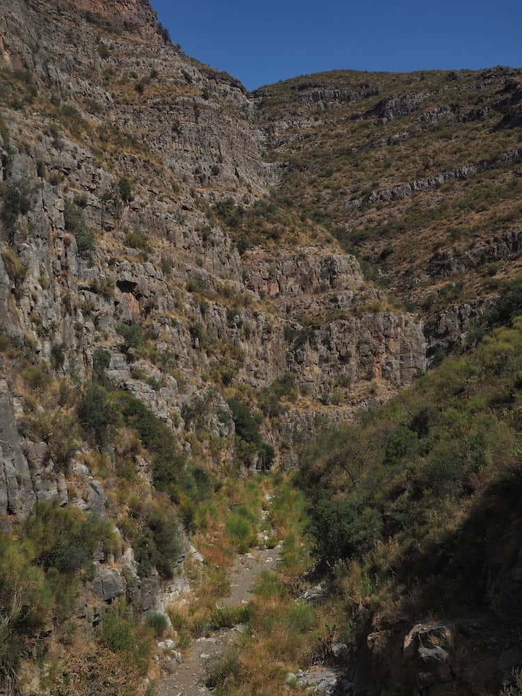 A dry river bed runs through a narrow gorge