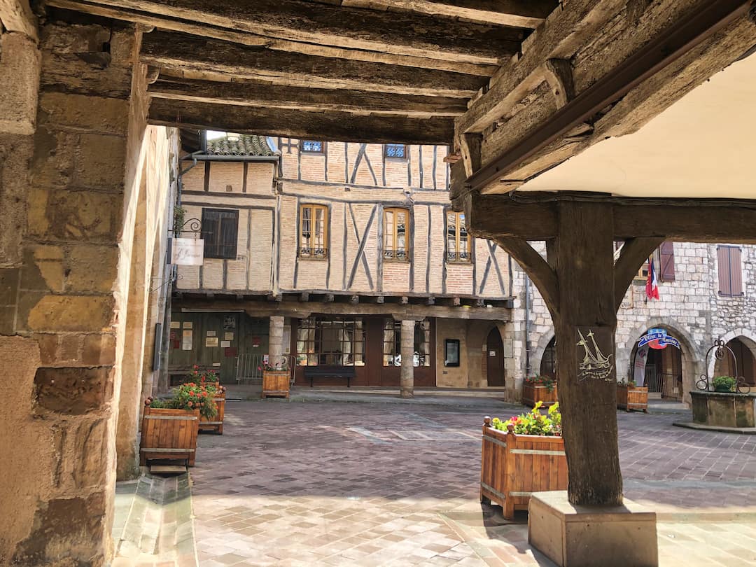 A view of a half-timbered building taken from under a wooden tunnel