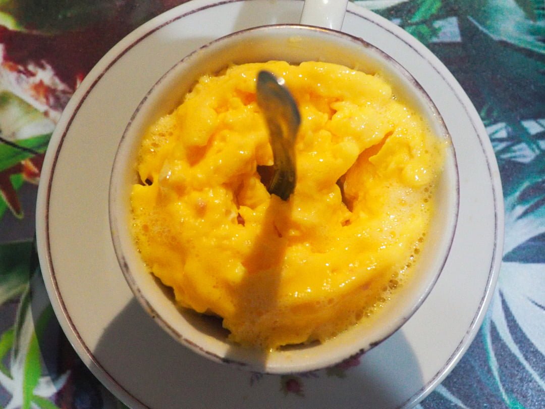 Looking down in to a bowl of yellow food with a spoon protruding from the centre