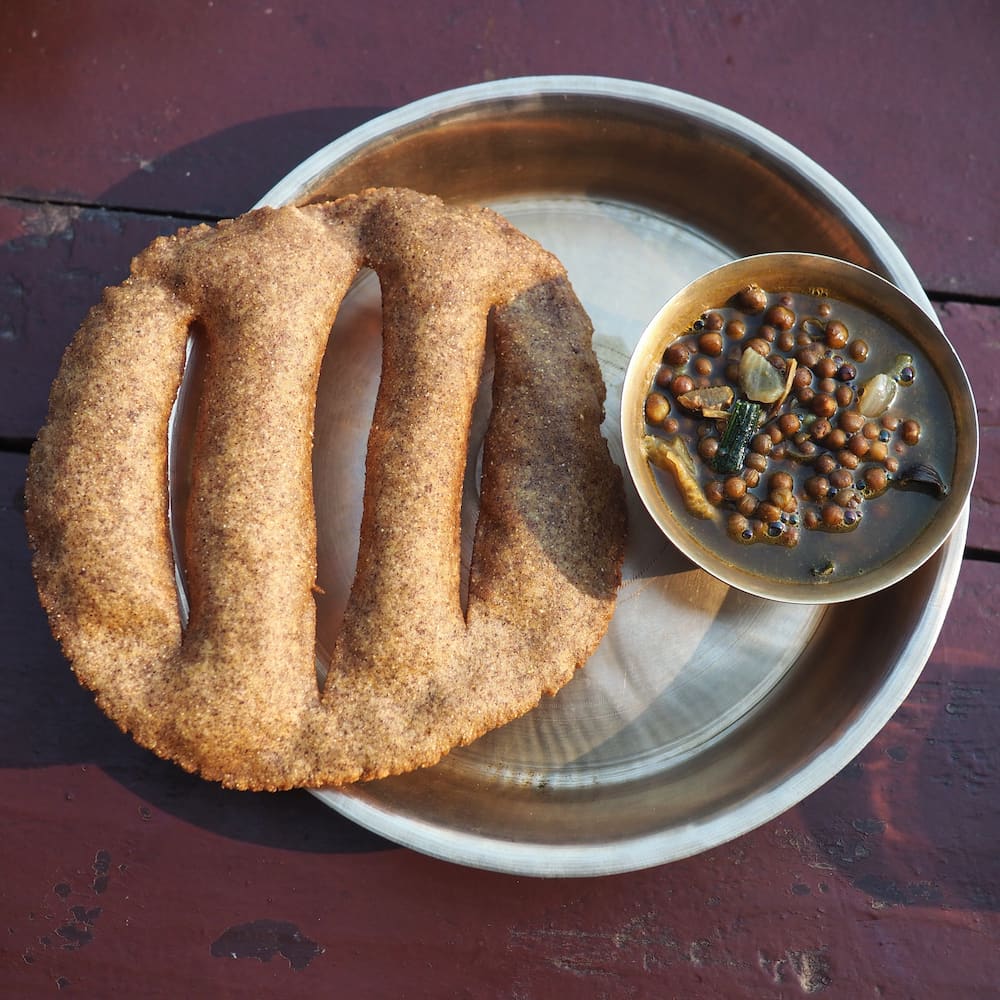 A circular piece of flatbread with slits through the middle and a small bowl of lentils