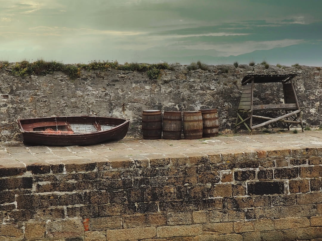 A rowing boat, rum barrels and a wooden structure on Charlestown's quayside