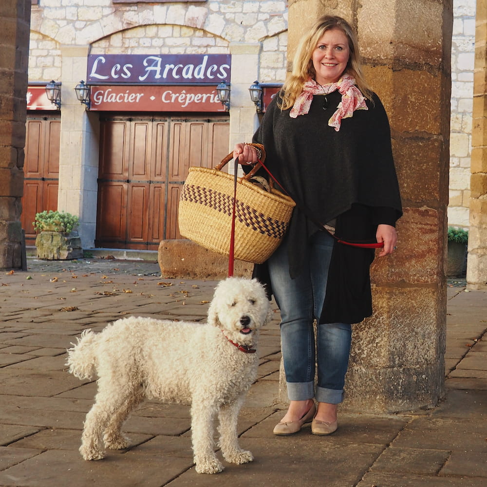 A woman holds a white dog on a lead