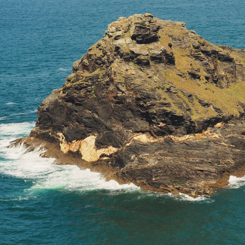 A rocky outcrop is battered by waves