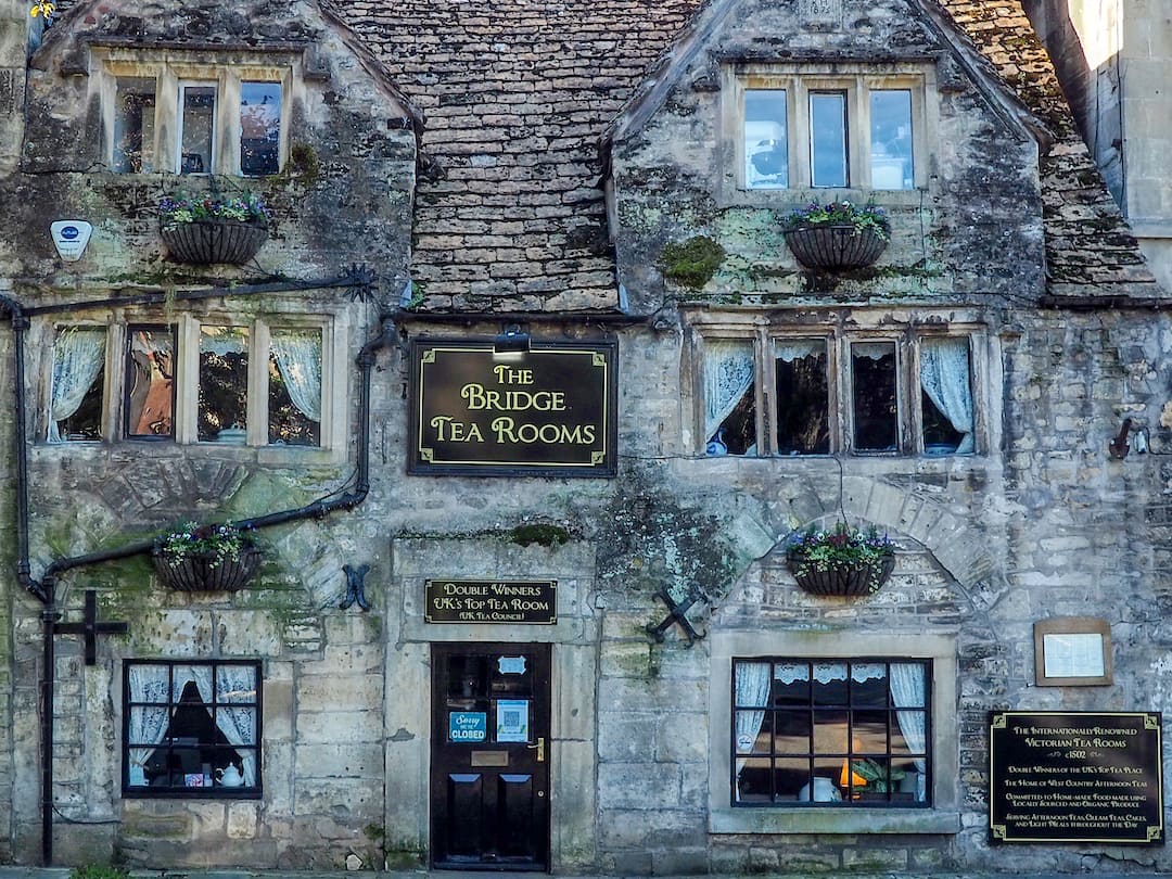 An ancient stone building with slate room and a square sign that reads "The Bridge Tea Rooms"
