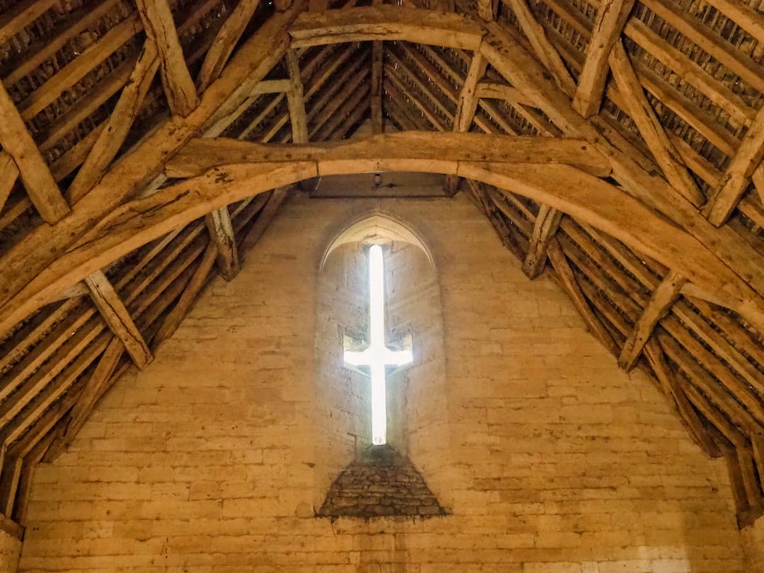 A close up of a detailed wooden ceiling and cross window
