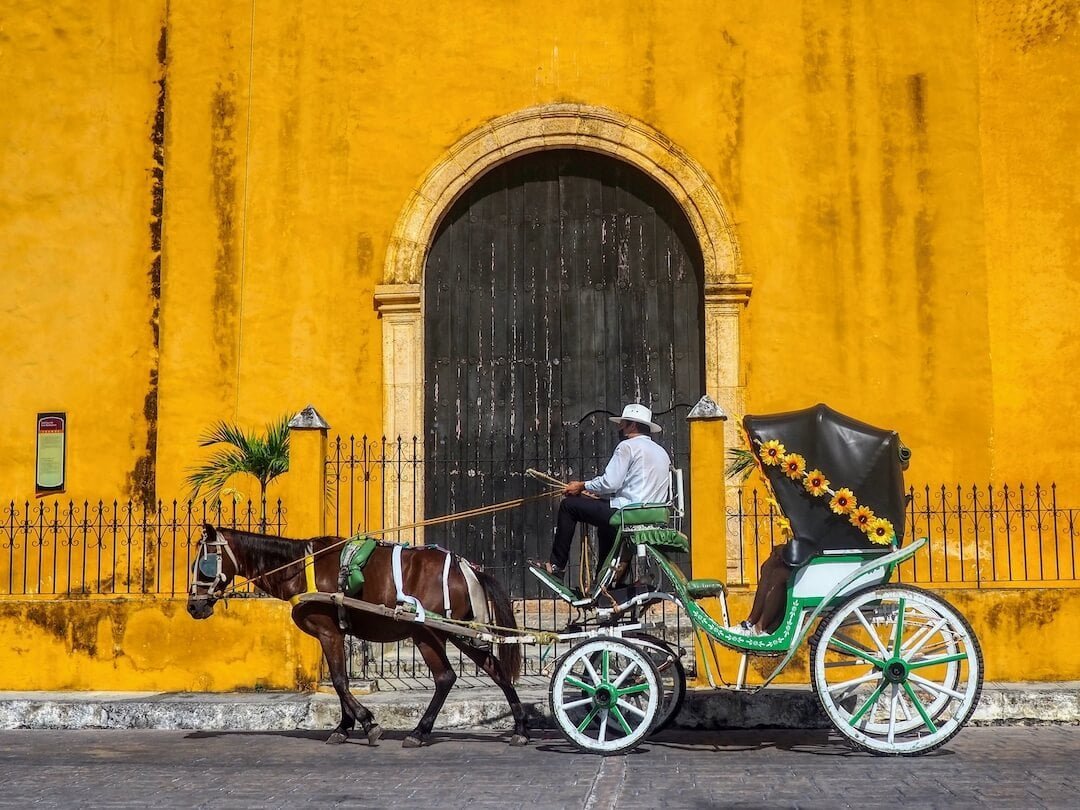A horse-drawe carriage in front of a yellow church