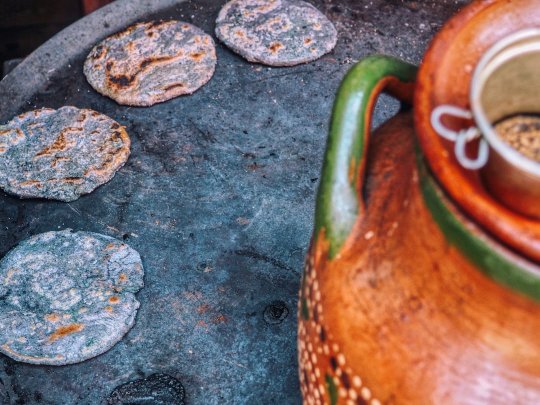 Blue corn tortillas being cooked on a comal