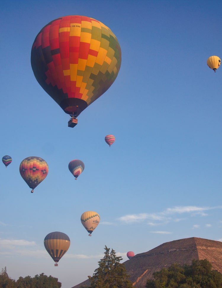 Hot air balloons hover above the Pyramid of the Sun