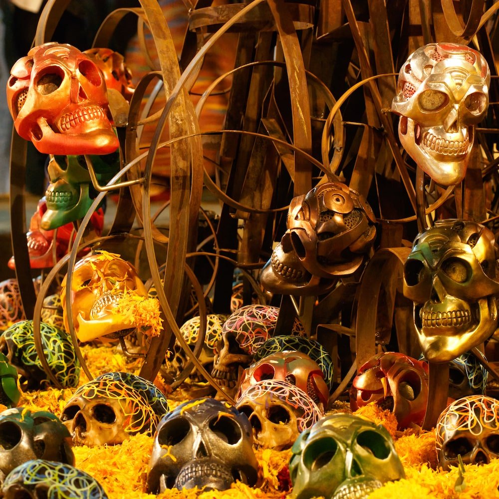 A metal display featuring skulls of different colours and orange marigolds