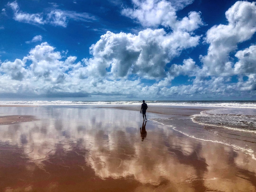 Clouds are reflected in the water-saturated sand